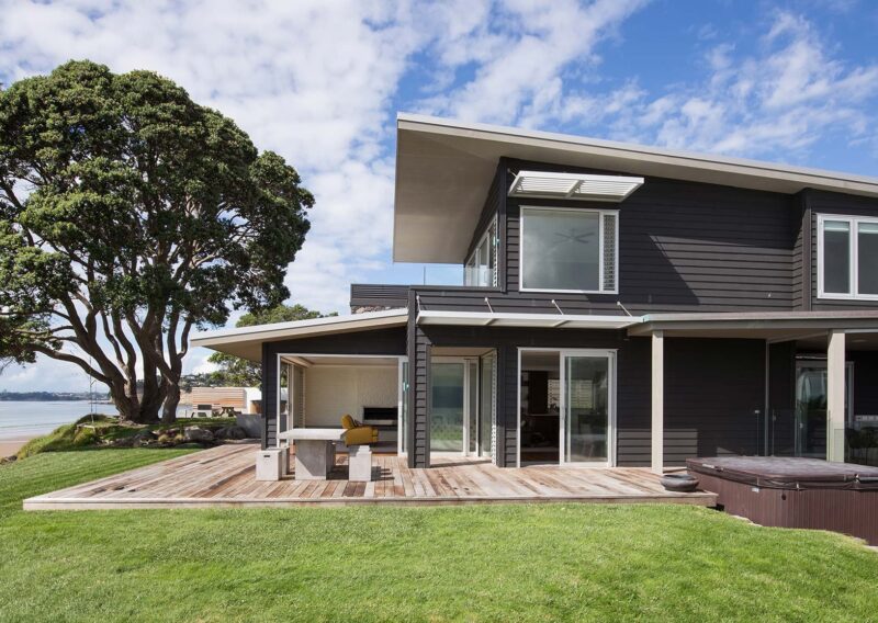 Accoya weather boards cladding around the Red Beach House in New Zealand. View from one side with the beach in view